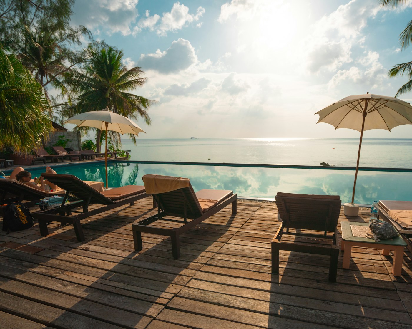 Infinity pool facing the sea with palm trees
